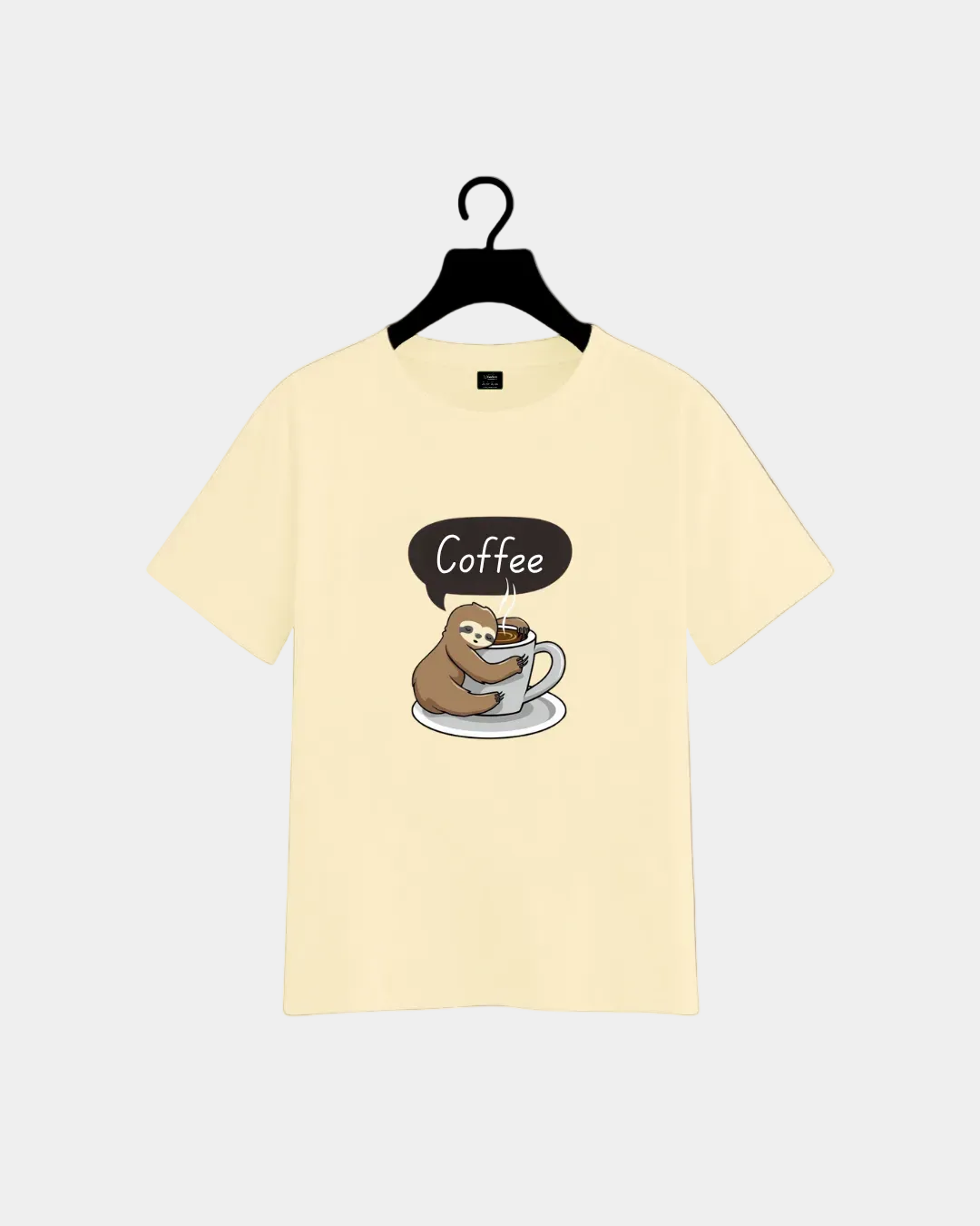 Beige t-shirt with a sloth holding a coffee cup graphic on a hanger against a gray background